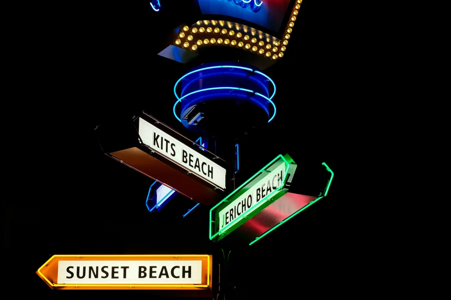 Neon sign with directional arrows for Kits Beach and nearby Vancouver beaches at night