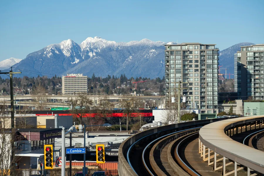 Richmond cityscape with SkyTrain tracks and snowy mountains in the distance