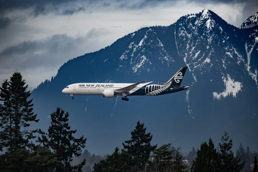 Air New Zealand plane flying past snowy mountains near Vancouver International Airport
