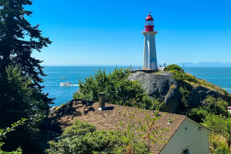 White and red lighthouse near trees and water in West Vancouver
