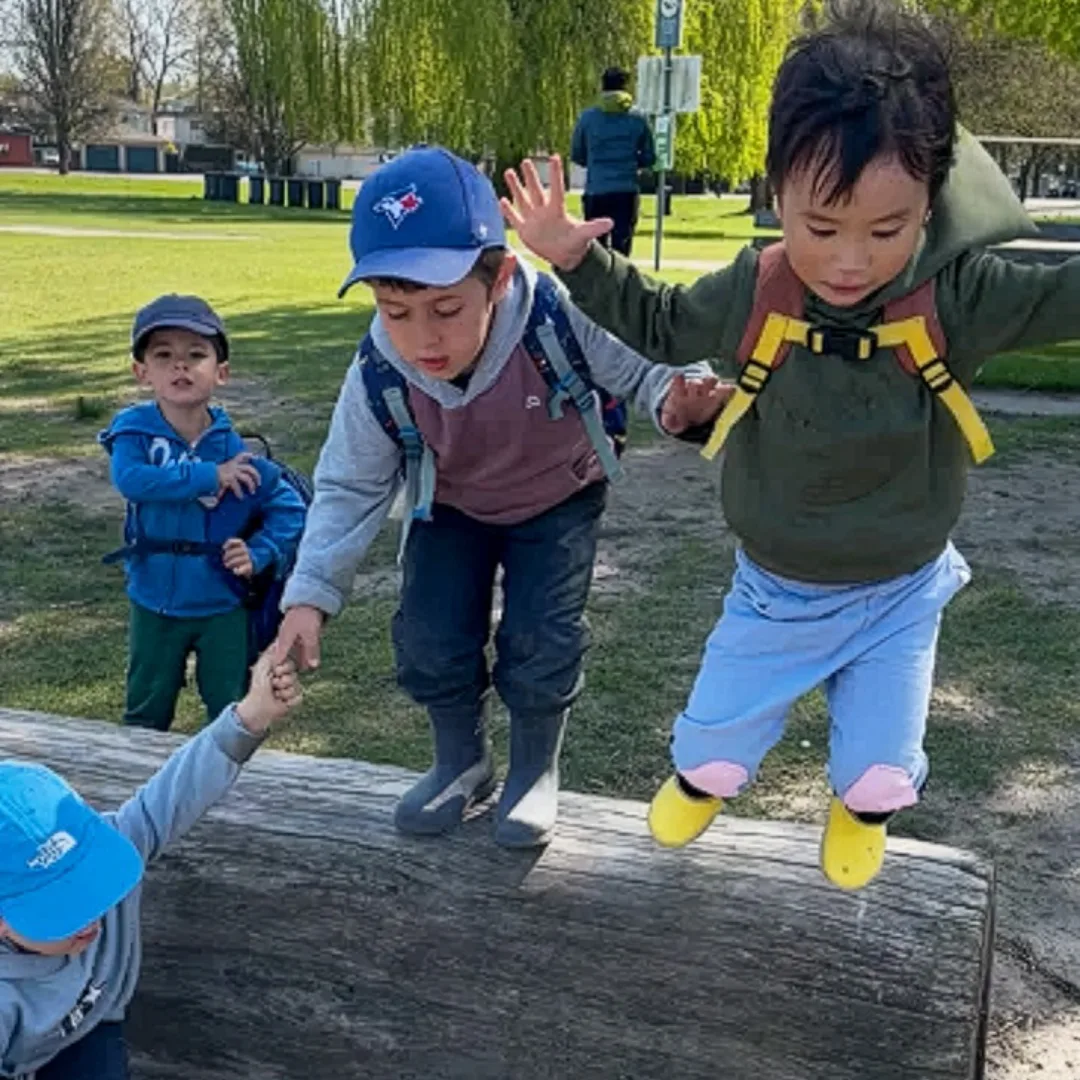 Children balancing on a log during outdoor camp.