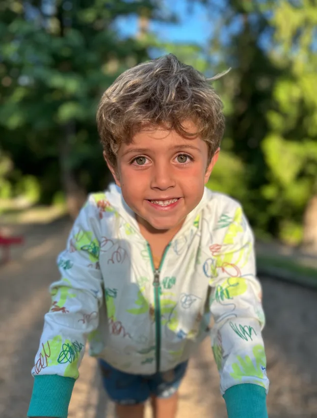 A child smiling outdoors during Sunhouse Outdoor Academy summer camp.
