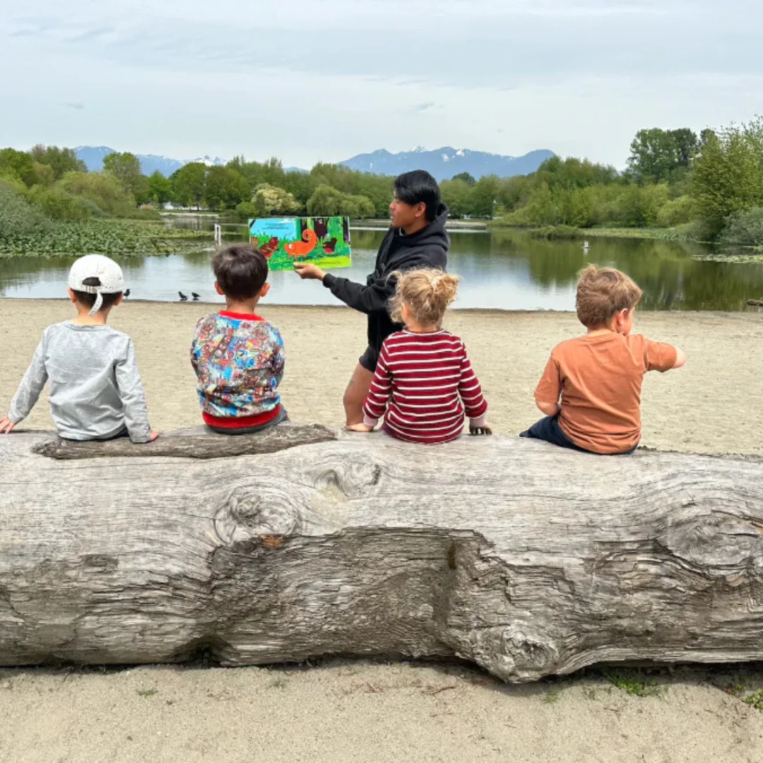 Children and an educator sitting beside Trout Lake during outdoor camp.